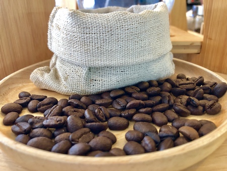Freshly roasted coffee beans In a cloth bag on a wooden floor.の写真素材