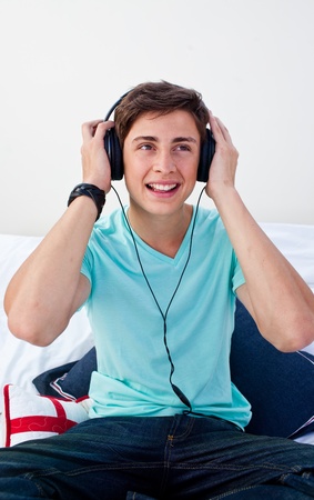 A teenage guy sitting on his bed listening to the musicの写真素材