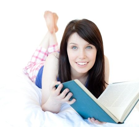 Portrait of a beautiul teen girl studying lying on a bed の写真素材