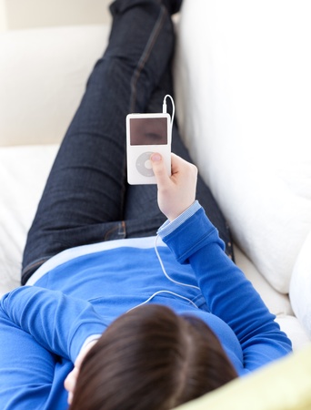 Close-up of a caucasian teen girl listening music lying on a sofa の写真素材