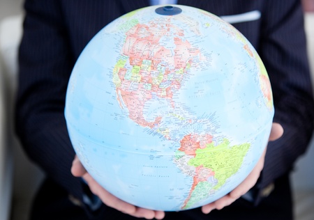 Close-up of a business person holding a terrestrial globeの写真素材