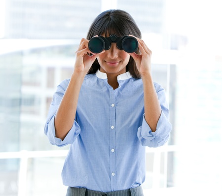 Assertive female executive looking through binoculars の写真素材