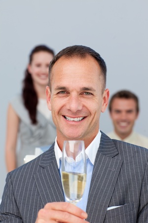 Successful businessman holding Champagne with his team の写真素材
