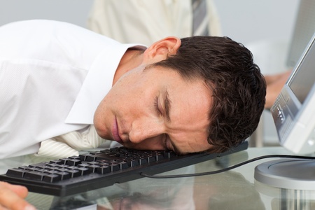 Businessman sleeping on the keyboard in the officeの写真素材