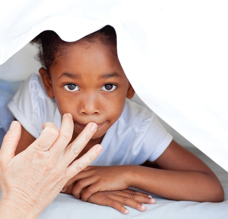 Portrait of a lovely little girl hidden under coverの写真素材