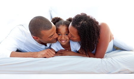 Cheerful parents kissing their daughterの写真素材