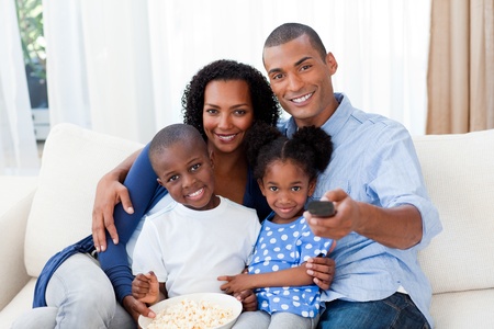 Smiling Afro-american family eating popcorn and watching TVの写真素材
