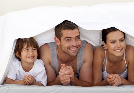 Son and parents playing under the bedsheetsの写真素材