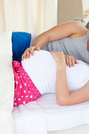 Close-up of a caucasian pregnant woman lying on bed with her husbandの写真素材