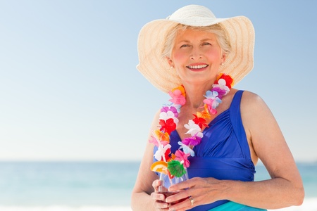 Elderly woman drinking a cocktail on the beachの写真素材