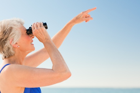 Senior woman bird watching at the beachの写真素材