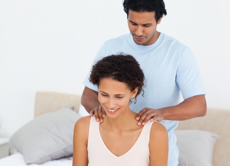 Handsome man doing a massage to his beautiful wife on their bed Handsome man doing a massage to his beautiful wife on their bed