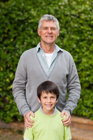 Grandfather with his grandson looking at the camera in the garden の写真素材