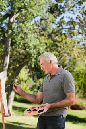 Mature man painting in the gardenの写真素材