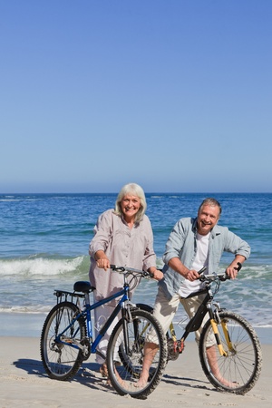 Mature couple with their bikes on the beachの写真素材