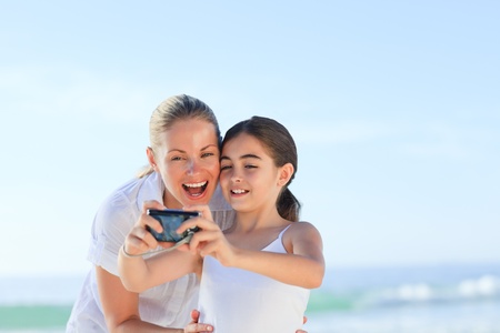 Little girl taking a photo of herself and her motherの写真素材