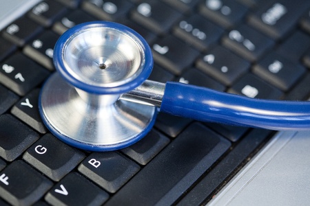 Blue angled stethoscope on keyboard on a blue backgroundの写真素材