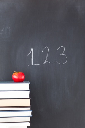 Stack of books with a red apple and a blackboard with "123" written on itの写真素材