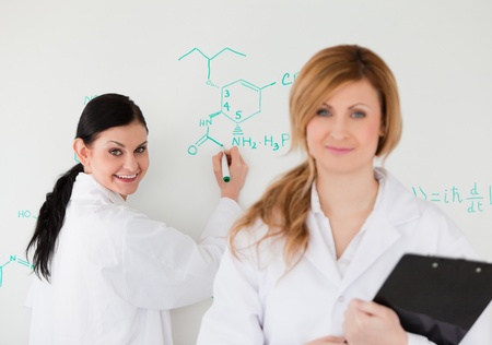 Two scientists looking at the camera while being in front of a white board in a labの写真素材
