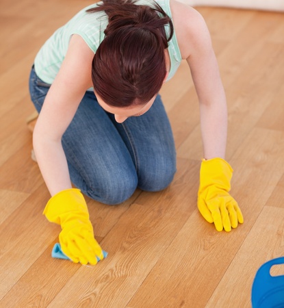 Attractive red-haired woman cleaning the floor while kneeling at homeの写真素材