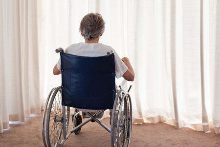 Mature woman in her wheelchair with her back to the camera at homeの写真素材