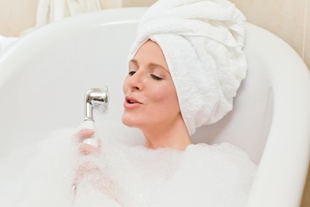 Charming woman taking a bath with a towel on her head 