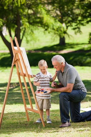 Grandfather and his grandson painting in the gardenの写真素材