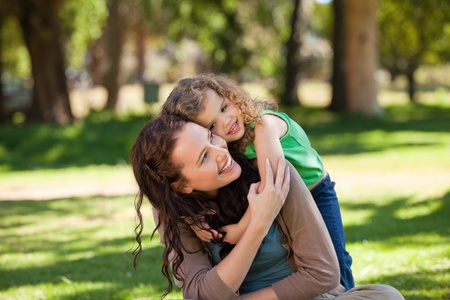 Woman hugging her daughter in the parkの写真素材
