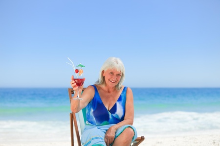 Elderly woman drinking a cocktail on the beachの写真素材