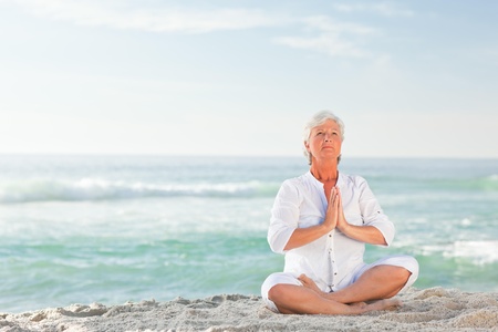 Mature woman practicing yoga on the beachの写真素材