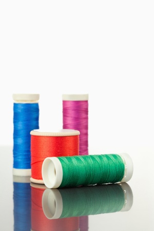 Colorful spools of thread on a table against a white background