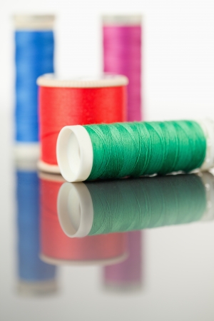 Colorful spools of thread on a table against a white background