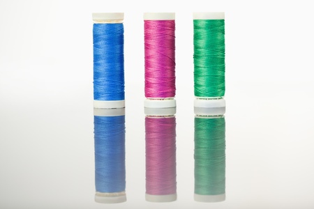 Colorful spools of thread on a table against a white background