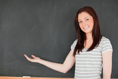 Smiling woman against blackboard with a copy space in a classroomの写真素材