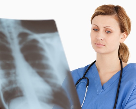 Concentrated female doctor looking at an X-ray on a white background