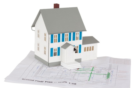 Gray toy house model on a ground floor plan against a white background