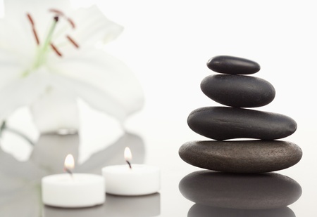 White orchid with lighted white candles and a black pebble stack the camera focus on the object