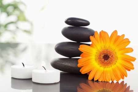 Lighted candles pebble stack an orange gerberaの写真素材