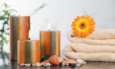 Lighted candles with an orange gerbera on towels and sea shellsの写真素材