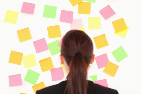 Red-haired woman looking at a wall full of repositional notes on a white wall