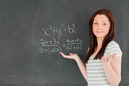 Smiling young woman solving an equation in a classroom