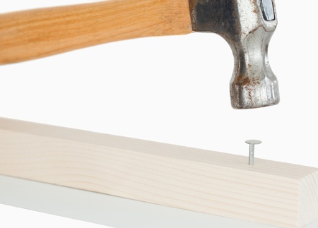 Hammer driving a nail against a white backgroundの写真素材