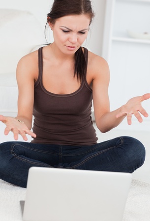 Close up of an angry dark-haired woman using her laptop in her living roomの写真素材