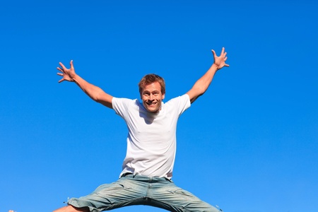 Portrait of a smiling Man jumping in the air outdoorの写真素材