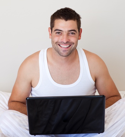 Glowing man using laptop sitting on a bed の写真素材