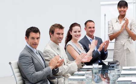 Business people applauding a colleague after reporting to sales figuresの写真素材