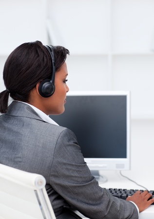 Serious businesswoman working at a computer with headset on in a call centerの写真素材