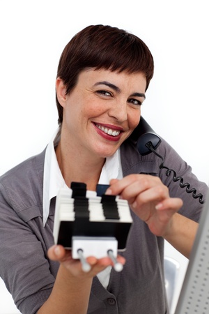 Smiling Businesswoman on phone consulting a business card holder の写真素材