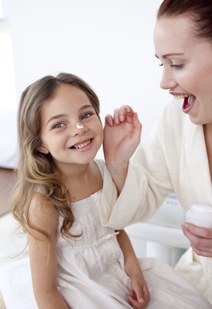 Happy mother putting cream on her daughter's faceの写真素材