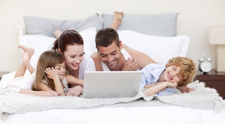 Family in bed using a laptopの写真素材